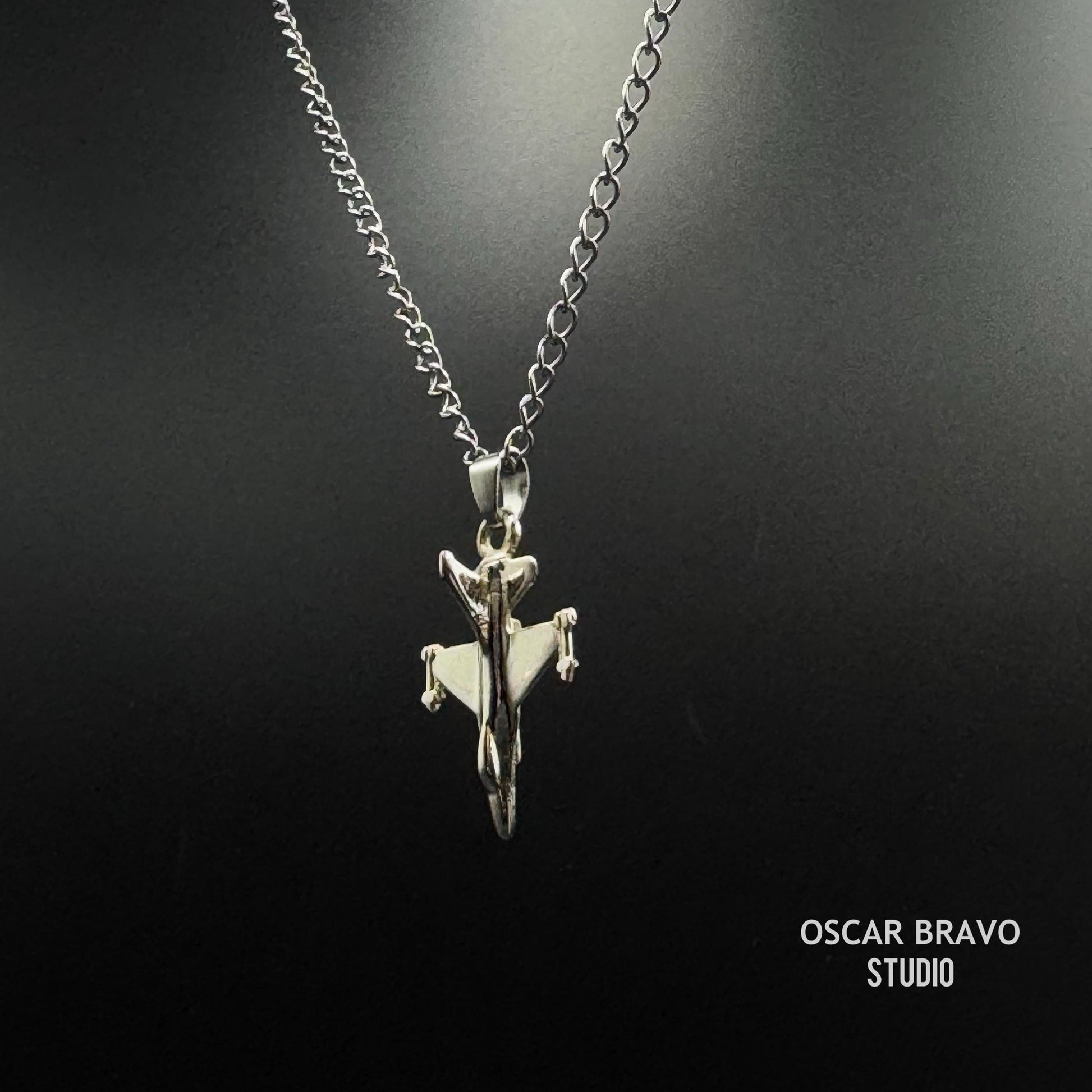 Silver airplane pendant necklace on a black background with 'Oscar Bravo Studio' branding.