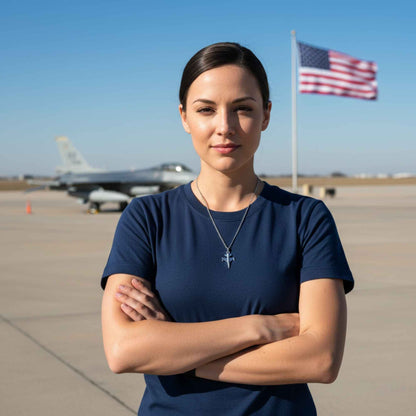 Woman standing with arms crossed on an airfield with a fighter jet and American flag in the background.